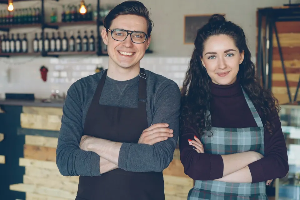 Deux commerçants souriants devant le comptoir de leur café